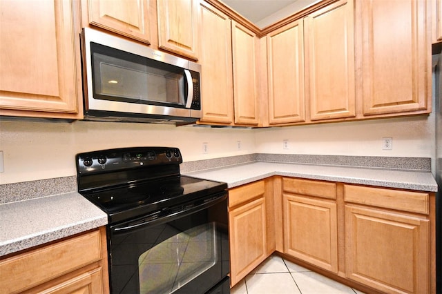 1086 Wickerwood St, Ocoee, FL 34761 - kitchen featuring black range with electric cooktop, stainless steel microwave, light brown cabinets, light tile patterned floors, and light countertops
