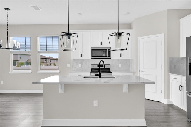 2311 Bear Peak Rd, Clermont, FL 34715 - kitchen with stainless steel appliances, dark wood-type flooring, decorative backsplash, and a kitchen island with sink