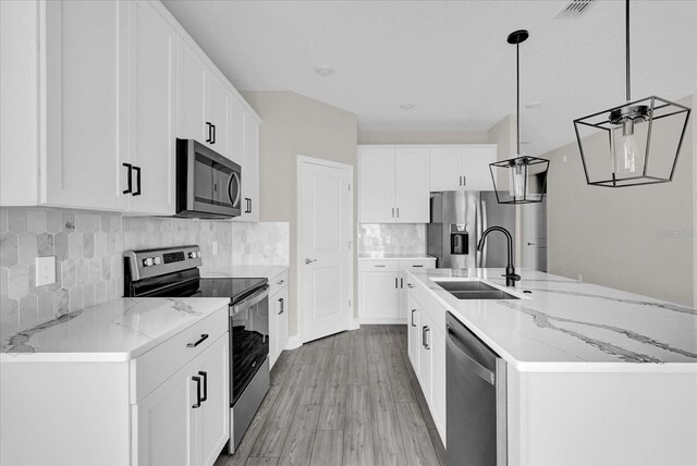2311 Bear Peak Rd, Clermont, FL 34715 - kitchen featuring appliances with stainless steel finishes, a center island with sink, white cabinetry, and light wood-style floors