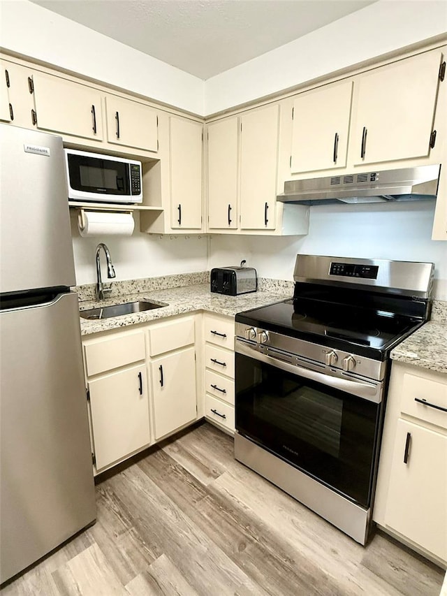 10301 US Highway 27 Unit 34, Clermont, FL 34711 - kitchen featuring stainless steel appliances, under cabinet range hood, a sink, and light wood-style floors