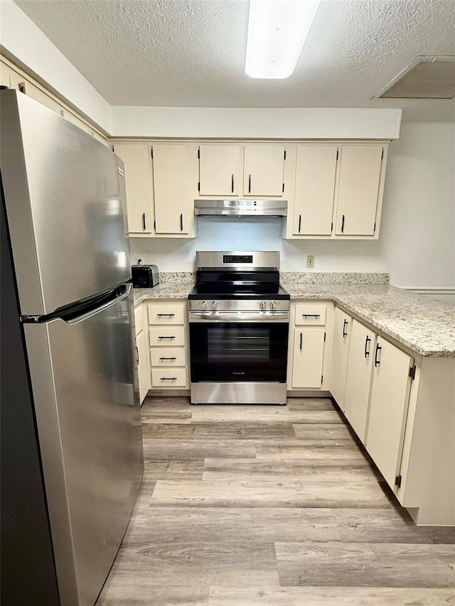 10301 US Highway 27 Unit 34, Clermont, FL 34711 - kitchen with appliances with stainless steel finishes, a textured ceiling, light wood-type flooring, under cabinet range hood, and a peninsula