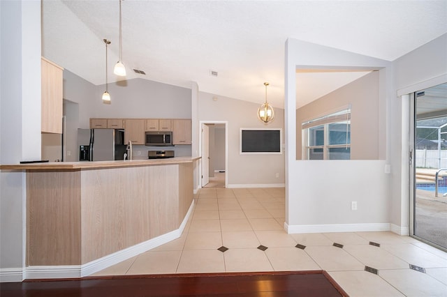1115 Marni Ridge Ct, Kissimmee, FL 34747 - kitchen with stainless steel appliances, light brown cabinetry, vaulted ceiling, light tile patterned floors, and light countertops