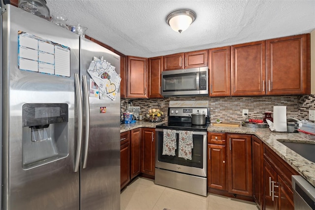 214 Majors Ln Unit B, Kissimmee, FL 34743 - kitchen with appliances with stainless steel finishes, light tile patterned flooring, light stone countertops, tasteful backsplash, and a textured ceiling