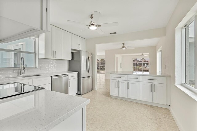 1764 Boca Raton Ct, Punta Gorda, FL 33950 - kitchen with stainless steel appliances, ceiling fan, a sink, light tile patterned flooring, and white cabinets