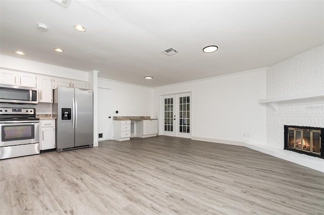 407 Ventura Dr, Sanford, FL 32773 - unfurnished living room with light wood-type flooring, french doors, recessed lighting, a brick fireplace, and baseboards