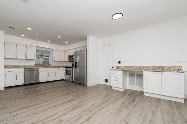 407 Ventura Dr, Sanford, FL 32773 - kitchen with appliances with stainless steel finishes, light wood finished floors, white cabinets, recessed lighting, and light stone countertops