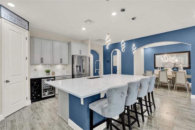 2390 Standing Rock Cir, Oakland, FL 34787 - kitchen featuring stainless steel fridge with ice dispenser, arched walkways, beverage cooler, light wood-type flooring, and recessed lighting