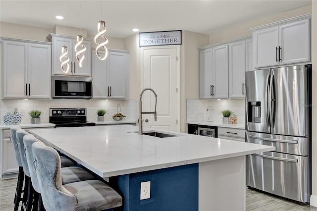 2390 Standing Rock Cir, Oakland, FL 34787 - kitchen featuring appliances with stainless steel finishes, light wood finished floors, a kitchen island with sink, tasteful backsplash, and pendant lighting