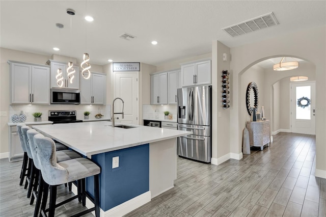 2390 Standing Rock Cir, Oakland, FL 34787 - kitchen featuring appliances with stainless steel finishes, arched walkways, an island with sink, backsplash, and light countertops