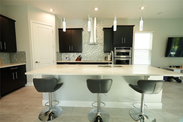 2035 White Feather Loop, Oakland, FL 34787 - kitchen with wall chimney exhaust hood, double oven, backsplash, light countertops, and a breakfast bar
