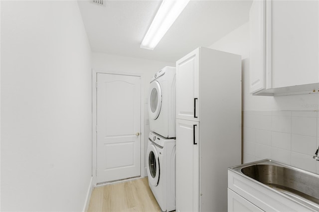 10001 Newington Dr, Orlando, FL 32836 - laundry room with stacked washer / drying machine, cabinet space, and light wood finished floors