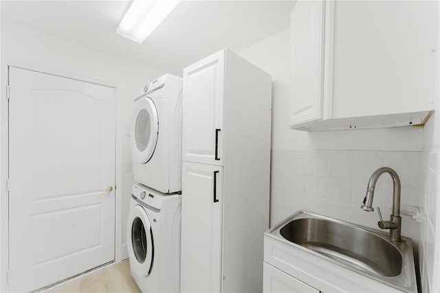 10001 Newington Dr, Orlando, FL 32836 - washroom featuring estacked washer and dryer, cabinet space, tile walls, and light wood finished floors