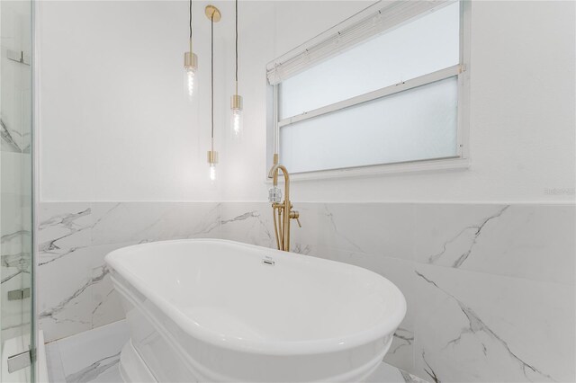 10001 Newington Dr, Orlando, FL 32836 - bathroom with a freestanding tub, marble finish floors, wainscoting, and tile walls