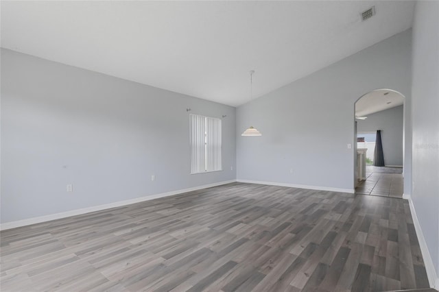 631 Lady Diana Dr, Davenport, FL 33837 - unfurnished room with plenty of natural light, wood finished floors, arched walkways, baseboards, and lofted ceiling