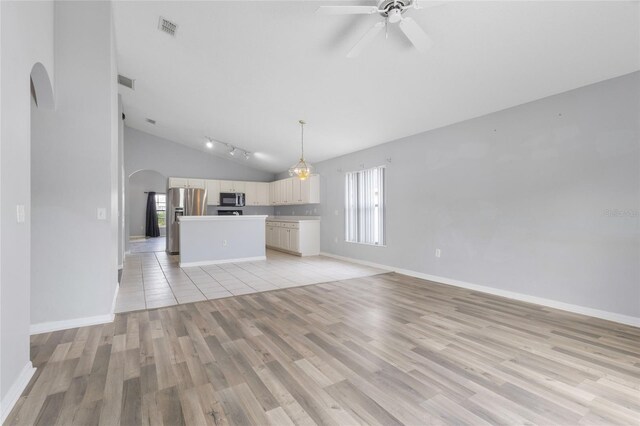 631 Lady Diana Dr, Davenport, FL 33837 - unfurnished living room with arched walkways, light wood-style floors, plenty of natural light, a ceiling fan, and high vaulted ceiling