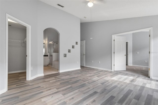 631 Lady Diana Dr, Davenport, FL 33837 - unfurnished bedroom featuring arched walkways, a walk in closet, light wood finished floors, ensuite bathroom, and high vaulted ceiling