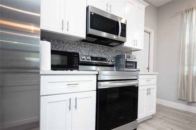 309 E 13th St, Apopka, FL 32703 - kitchen with stainless steel appliances, decorative backsplash, light countertops, baseboards, and white cabinetry