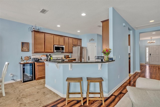 11616 Thacker Dr, Clermont, FL 34711 - kitchen featuring wine cooler, appliances with stainless steel finishes, brown cabinets, a kitchen breakfast bar, and recessed lighting
