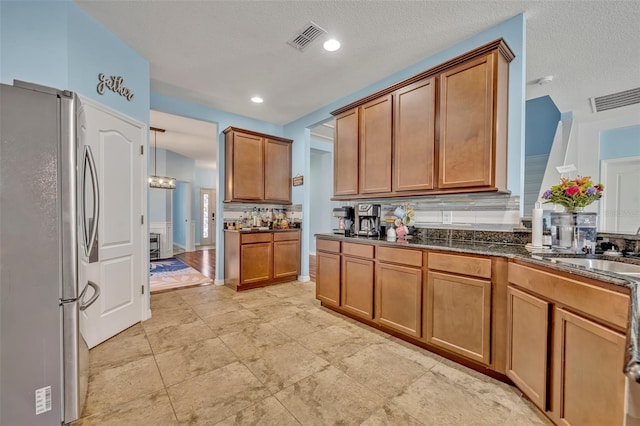 11616 Thacker Dr, Clermont, FL 34711 - kitchen with freestanding refrigerator, brown cabinets, backsplash, and dark stone counters