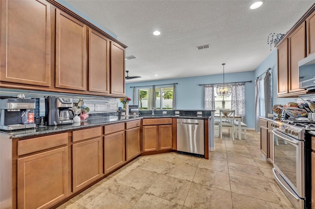 11616 Thacker Dr, Clermont, FL 34711 - kitchen with stainless steel appliances, a peninsula, brown cabinetry, recessed lighting, and dark stone countertops