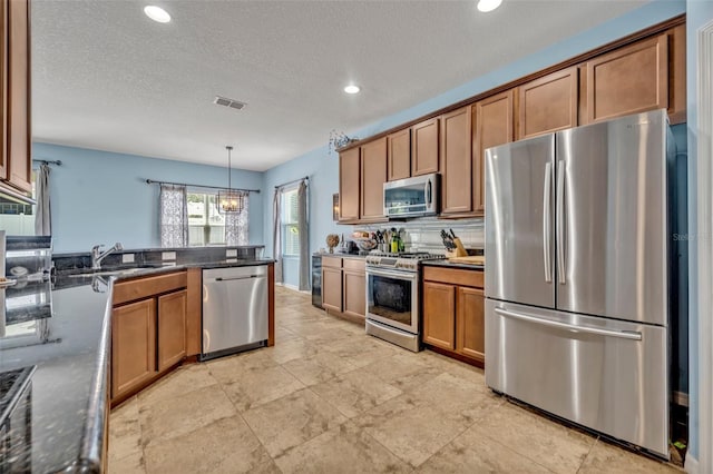 11616 Thacker Dr, Clermont, FL 34711 - kitchen with appliances with stainless steel finishes, brown cabinetry, dark stone countertops, recessed lighting, and hanging light fixtures