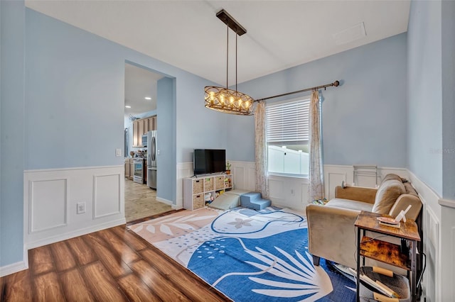 11616 Thacker Dr, Clermont, FL 34711 - living area with wainscoting, wood finished floors, a decorative wall, and a chandelier