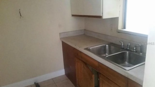 2260 Willie Mays Pkwy, Orlando, FL 32811 - kitchen with a sink, light countertops, light tile patterned floors, white cabinets, and baseboards