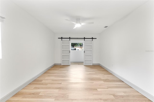 7446 Houston Ct E, Winter Park, FL 32792 - spare room featuring a barn door, light wood-style flooring, baseboards, and ceiling fan