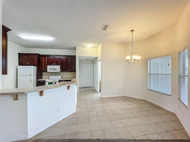 36730 Oconee Ave, Eustis, FL 32736 - kitchen with white appliances, a kitchen bar, a chandelier, light countertops, and light tile patterned floors