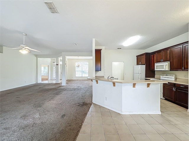 36730 Oconee Ave, Eustis, FL 32736 - kitchen featuring white appliances, open floor plan, a breakfast bar, light countertops, and a peninsula