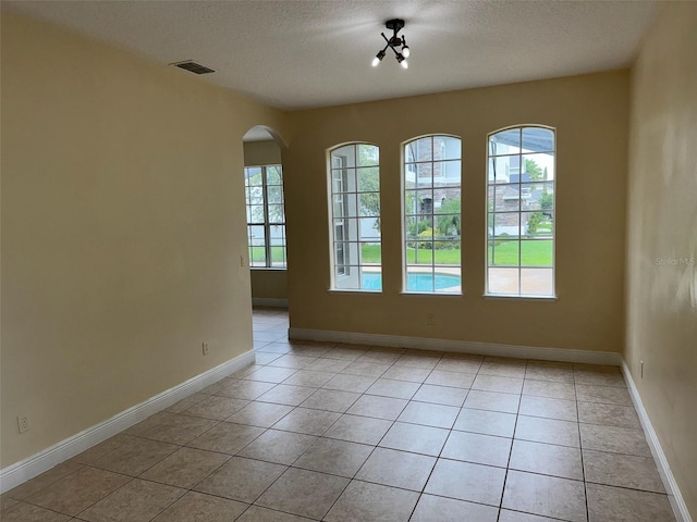 14508 Cedar Branch Way, Orlando, FL 32824 - unfurnished room with light tile patterned floors, a textured ceiling, arched walkways, and baseboards