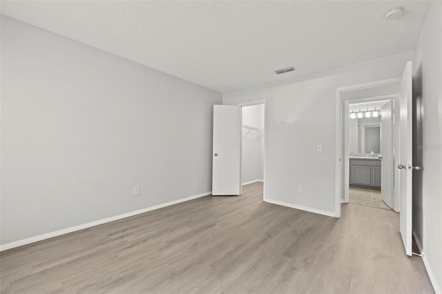 5436 E Michigan St Unit 7, Orlando, FL 32812 - unfurnished bedroom with a textured ceiling, light wood-style flooring, a spacious closet, and a closet