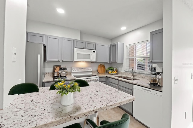 5436 E Michigan St Unit 7, Orlando, FL 32812 - kitchen featuring white appliances, gray cabinets, a kitchen bar, light stone counters, and recessed lighting