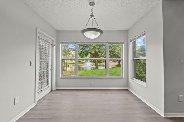 5436 E Michigan St Unit 7, Orlando, FL 32812 - unfurnished dining area featuring a textured ceiling, wood finished floors, and a water view