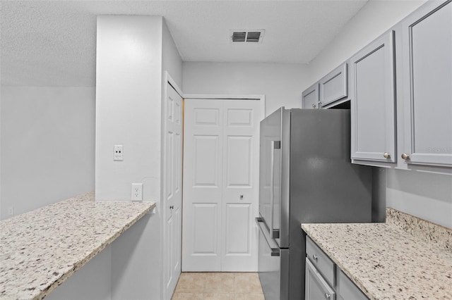 5436 E Michigan St Unit 7, Orlando, FL 32812 - kitchen featuring freestanding refrigerator, gray cabinets, light stone counters, light tile patterned flooring, and a textured ceiling