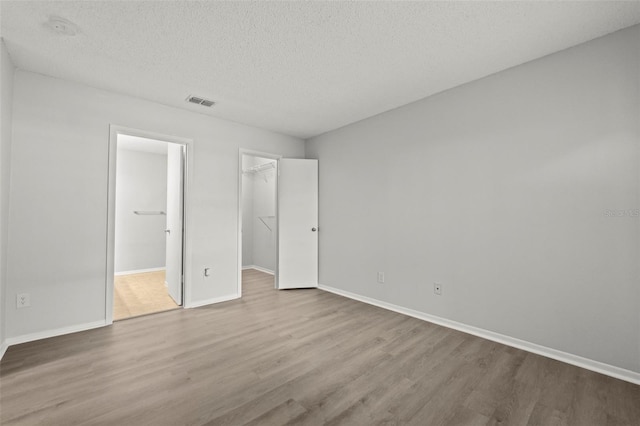 5436 E Michigan St Unit 7, Orlando, FL 32812 - unfurnished bedroom featuring wood finished floors, a spacious closet, a textured ceiling, a closet, and ensuite bath