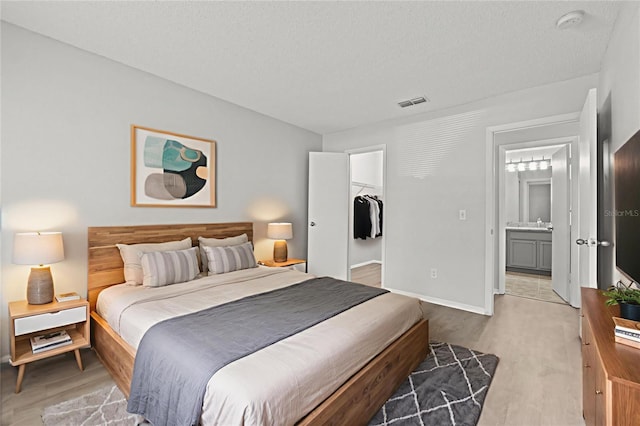5436 E Michigan St Unit 7, Orlando, FL 32812 - bedroom with light wood-style floors, a walk in closet, and a textured ceiling
