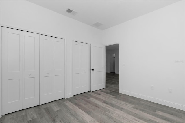 9419 N Jackson Way, Citrus Springs, FL 34434 - unfurnished bedroom with wood finished floors, baseboards, and two closets