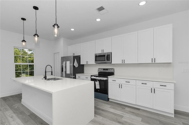 9419 N Jackson Way, Citrus Springs, FL 34434 - kitchen with stainless steel appliances, a sink, an island with sink, white cabinetry, and light wood-type flooring