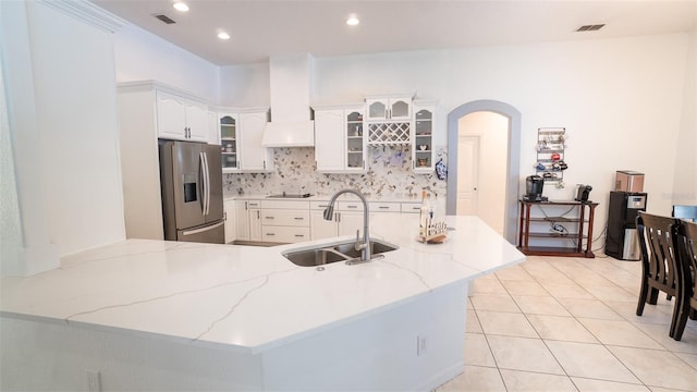 19951 Quinlan St, Orlando, FL 32833 - kitchen with stainless steel fridge, a peninsula, light stone countertops, glass insert cabinets, and decorative backsplash