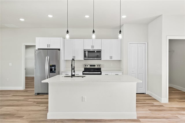178 Marion Oaks Ln, Ocala, FL 34473 - kitchen with appliances with stainless steel finishes, a sink, light wood finished floors, white cabinets, and a center island with sink
