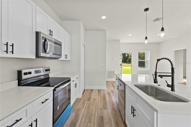 178 Marion Oaks Ln, Ocala, FL 34473 - kitchen with stainless steel appliances, a sink, light wood-style flooring, decorative light fixtures, and white cabinets