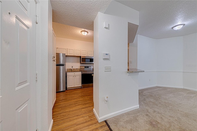 5500 Metrowest Blvd Unit 203, Orlando, FL 32811 - hallway with a textured ceiling, baseboards, and light wood-style flooring