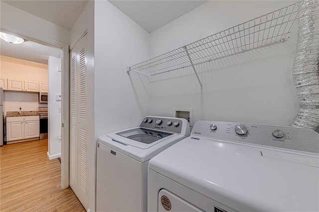 5500 Metrowest Blvd Unit 203, Orlando, FL 32811 - washroom featuring washing machine and dryer, light wood-style flooring, and a textured ceiling