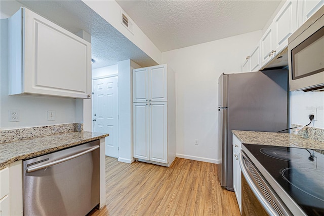 5500 Metrowest Blvd Unit 203, Orlando, FL 32811 - kitchen featuring stainless steel appliances, light wood-type flooring, white cabinetry, a textured ceiling, and baseboards