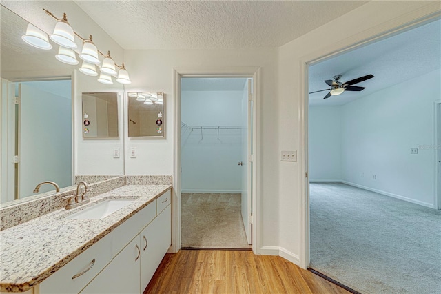 5500 Metrowest Blvd Unit 203, Orlando, FL 32811 - bathroom with vanity, wood finished floors, a textured ceiling, ceiling fan, and baseboards