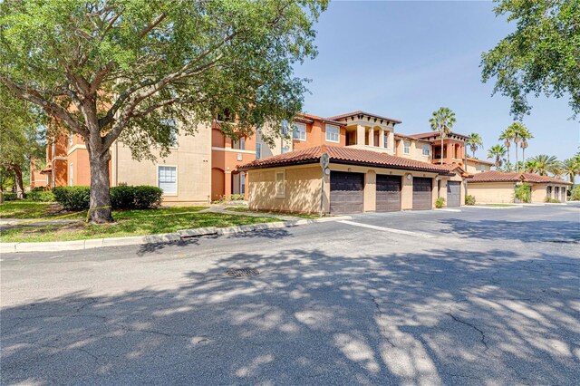 5500 Metrowest Blvd Unit 203, Orlando, FL 32811 - view of front of home featuring a tiled roof, stucco siding, and asphalt driveway