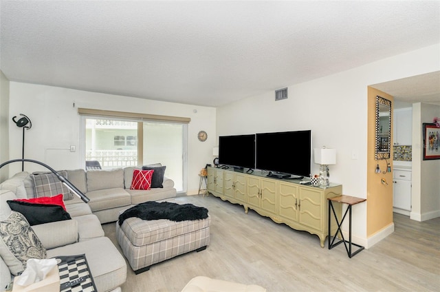 4850 Ocean Beach Blvd Unit 208, Cocoa Beach, FL 32931 - living room featuring light wood-style floors, a textured ceiling, and baseboards