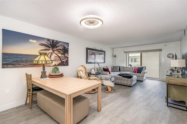 4850 Ocean Beach Blvd Unit 208, Cocoa Beach, FL 32931 - dining room featuring light wood-style floors, a textured ceiling, and baseboards
