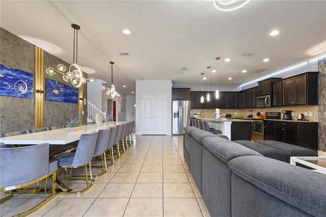 8801 Macapa Dr, Kissimmee, FL 34747 - kitchen with stainless steel appliances, open floor plan, light tile patterned floors, a kitchen breakfast bar, and light countertops